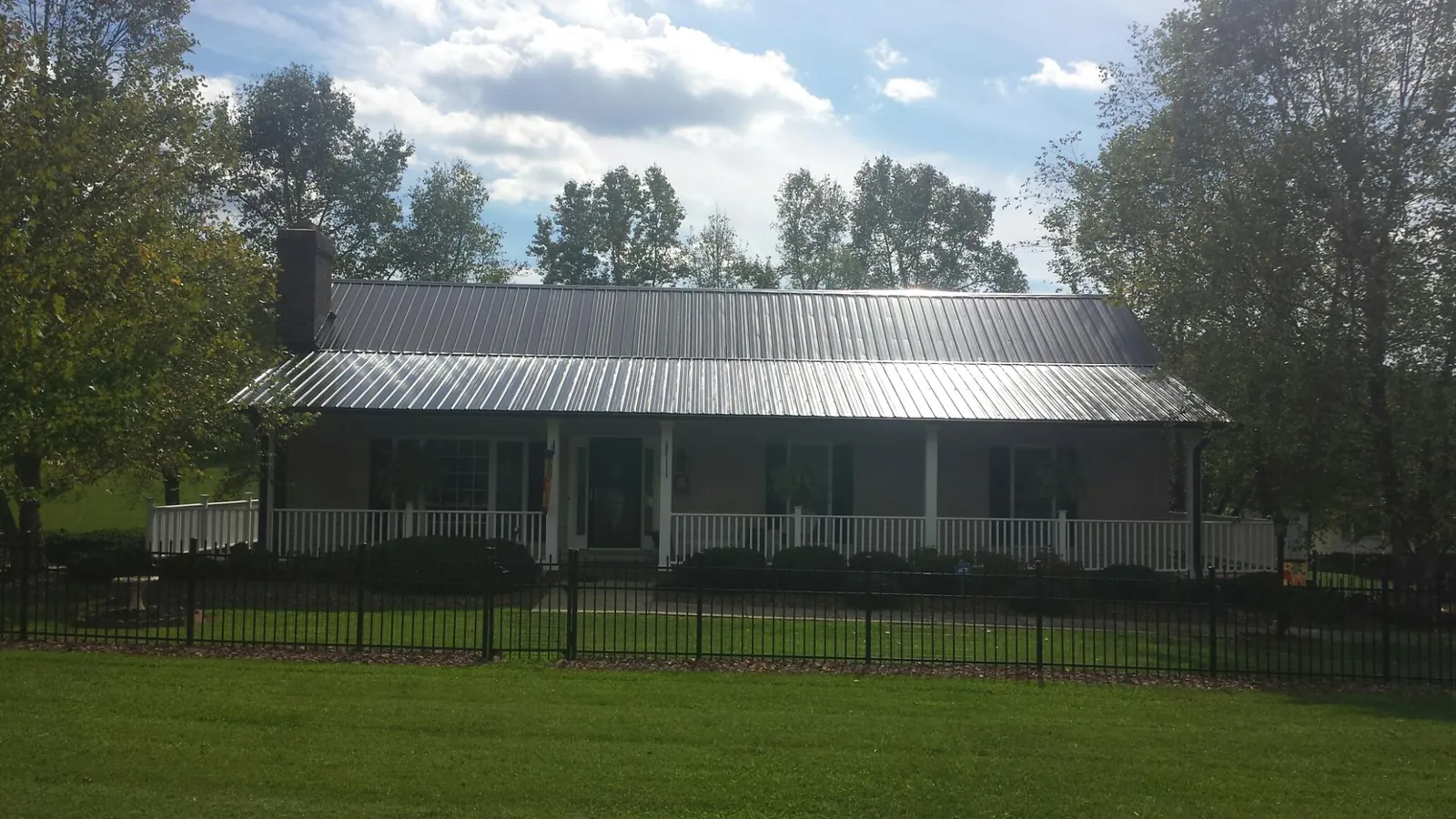 Gray metal roof on a brick ranch with a full width front porch — Gutter Guard Installation work by our crew in South Londonderry