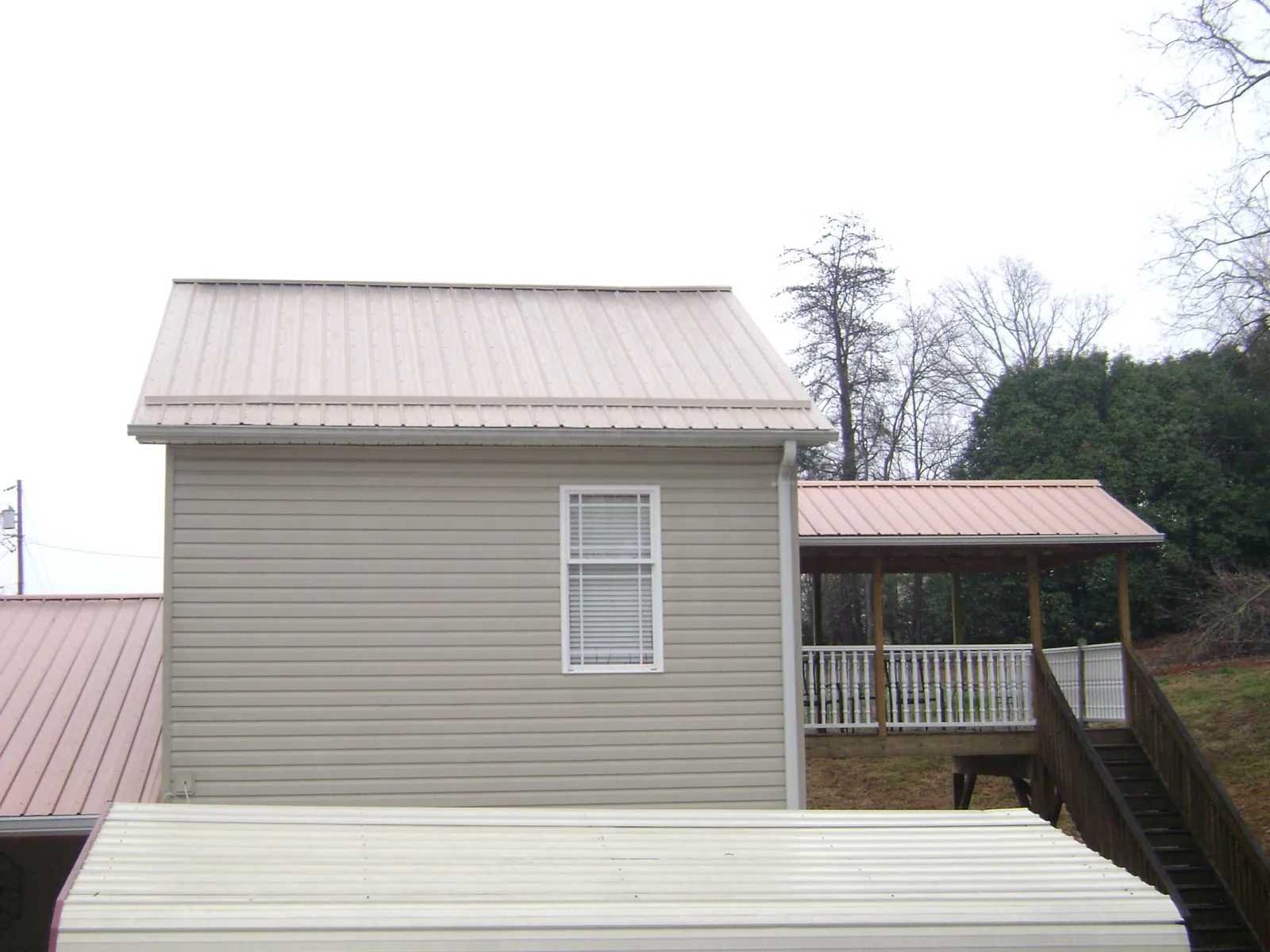 Tan metal roofs on a two story addition and attached porch, from a Roof Replacement job in South Londonderry