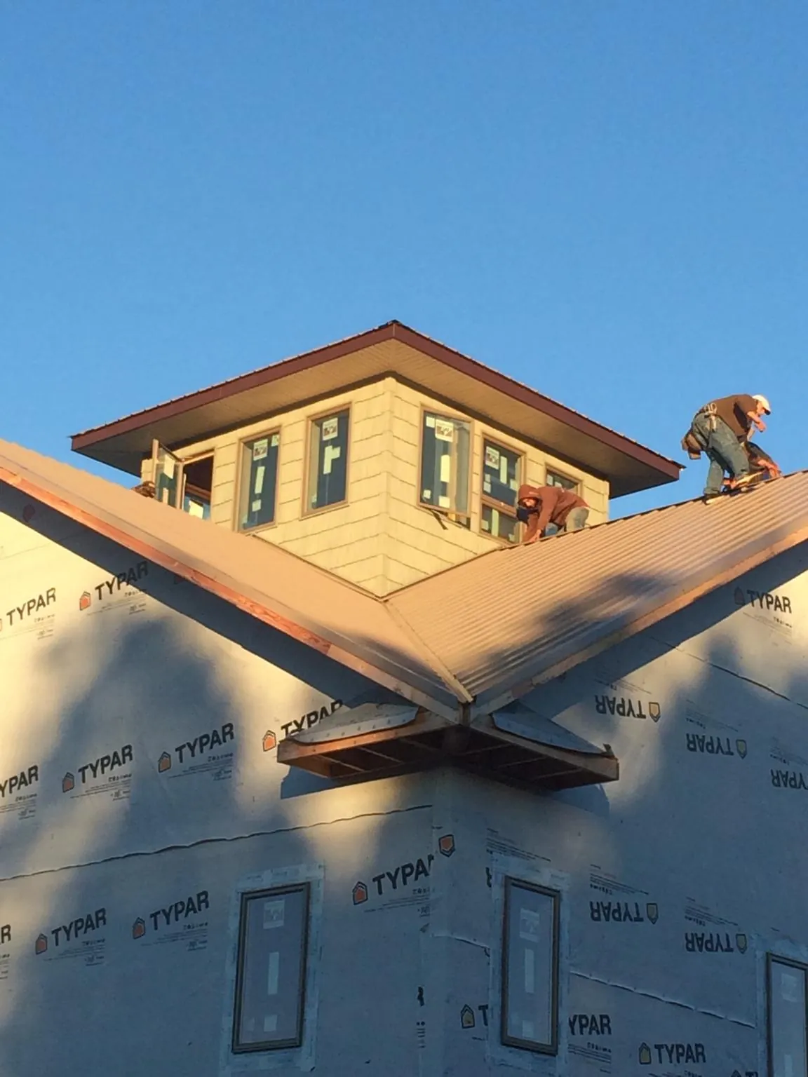 Roofers working around a rooftop cupola on a new metal roof at sunset — Roof Waterproofing in South Londonderry by Roofing Brothers